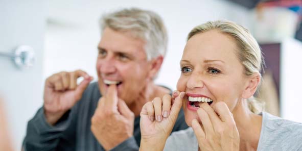 Paar mit Zahnseide: Implantate trotz Zahnfleischentzündung.
